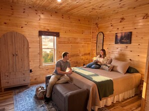 Interior acogedor de una cabaña con cama, ventana, espejo y puerta.