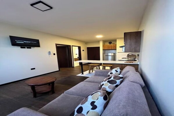 Ein modernes Wohnzimmer mit einer Couch, einem Couchtisch und einem an der Wand befestigten Fernseher.