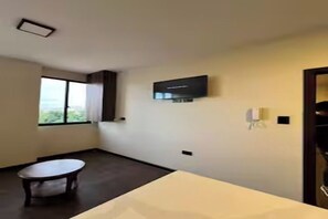 Une chambre d’hôtel avec un lit, un téléviseur fixé au mur, une fenêtre et une petite table.