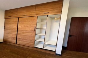 Une pièce avec une armoire en bois, une étagère blanche et une porte.