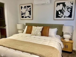 A neatly made bed with a beige comforter, a green headboard, and two bedside lamps.