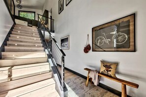 A staircase with wooden steps and metal railings, a framed bicycle artwork on the wall, and a bench with a cushion. - New 2023 Built, 5-bedroom Tahoe Donner house in Truckee with AC + Meadow Views (Truckee)