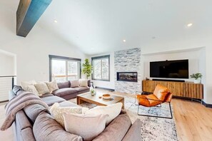 A modern living room with a sectional sofa, a coffee table, a fireplace, and a television. - New 2023 Built, 5-bedroom Tahoe Donner house in Truckee with AC + Meadow Views (Truckee)