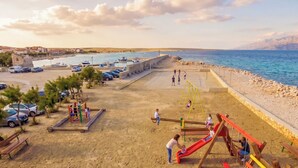 Una spiaggia con un'area giochi, auto e vista sul mare.