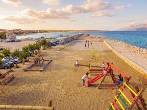 Ein Strand mit Spielplatz, Autos und Blick aufs Meer.