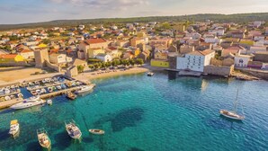 Una cittadina costiera con un porto turistico, case e un edificio bianco imponente.