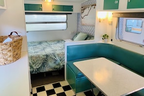 Ein kompaktes Wohnmobil-Interieur mit Bett, Essbereich und einer kleinen Küchenzeile.