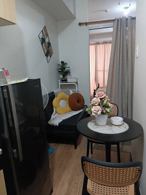 Ein gemütlicher Wohnraum mit Sofa, Esstisch, Stuhl, kleiner Topfpflanze und Zierkissen.