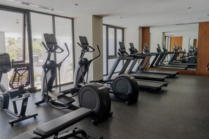 Ein Fitnessraum mit Laufbändern, Crosstrainern und Gewichtsbänken.