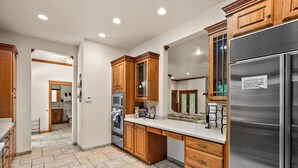 A modern kitchen with wooden cabinets, a stainless steel refrigerator, and a tiled floor.