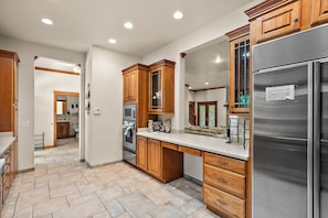 Una cocina moderna con armarios de madera, un refrigerador de acero inoxidable y suelo de baldosas.