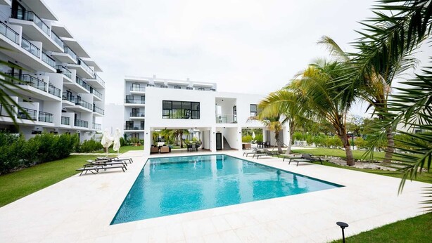 Un edificio moderno con piscina, area relax all'aperto e vegetazione.