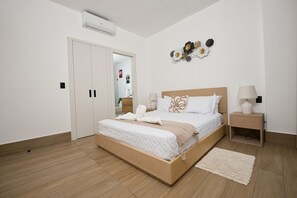 Ein Schlafzimmer mit einem hölzernen Bett, weißer Bettwäsche, einem Nachttisch mit Lampe und einer Wanddekoration.