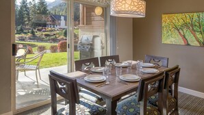 A dining area with a table set for six, chairs with patterned upholstery, a hanging light fixture, and a sliding glass door leading to an outdoor patio. - Vacation Winter Getaways at Leavenworth (Leavenworth)