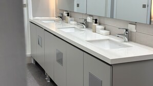 Een moderne badkamer met een lange wastafel, twee wasbakken en een grote spiegel.