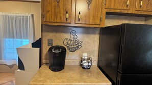 A kitchen with wooden cabinets, a coffee maker, a black refrigerator, and a window with a curtain. - Steps from Lake Fork w/ private boat ramp access! (Emory)