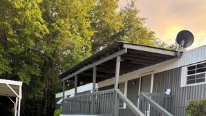 A building with a covered porch, a satellite dish, and a staircase leading to a deck. - Steps from Lake Fork w/ private boat ramp access! (Emory)