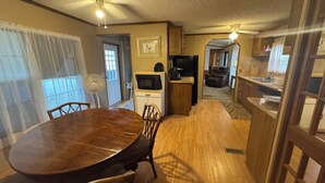 A compact kitchen with a microwave, refrigerator, and a dining area with a wooden table and chairs. - Steps from Lake Fork w/ private boat ramp access! (Emory)