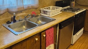 A kitchen with a double sink, wooden cabinets, a stove, and a window with sheer curtains. - Steps from Lake Fork w/ private boat ramp access! (Emory)