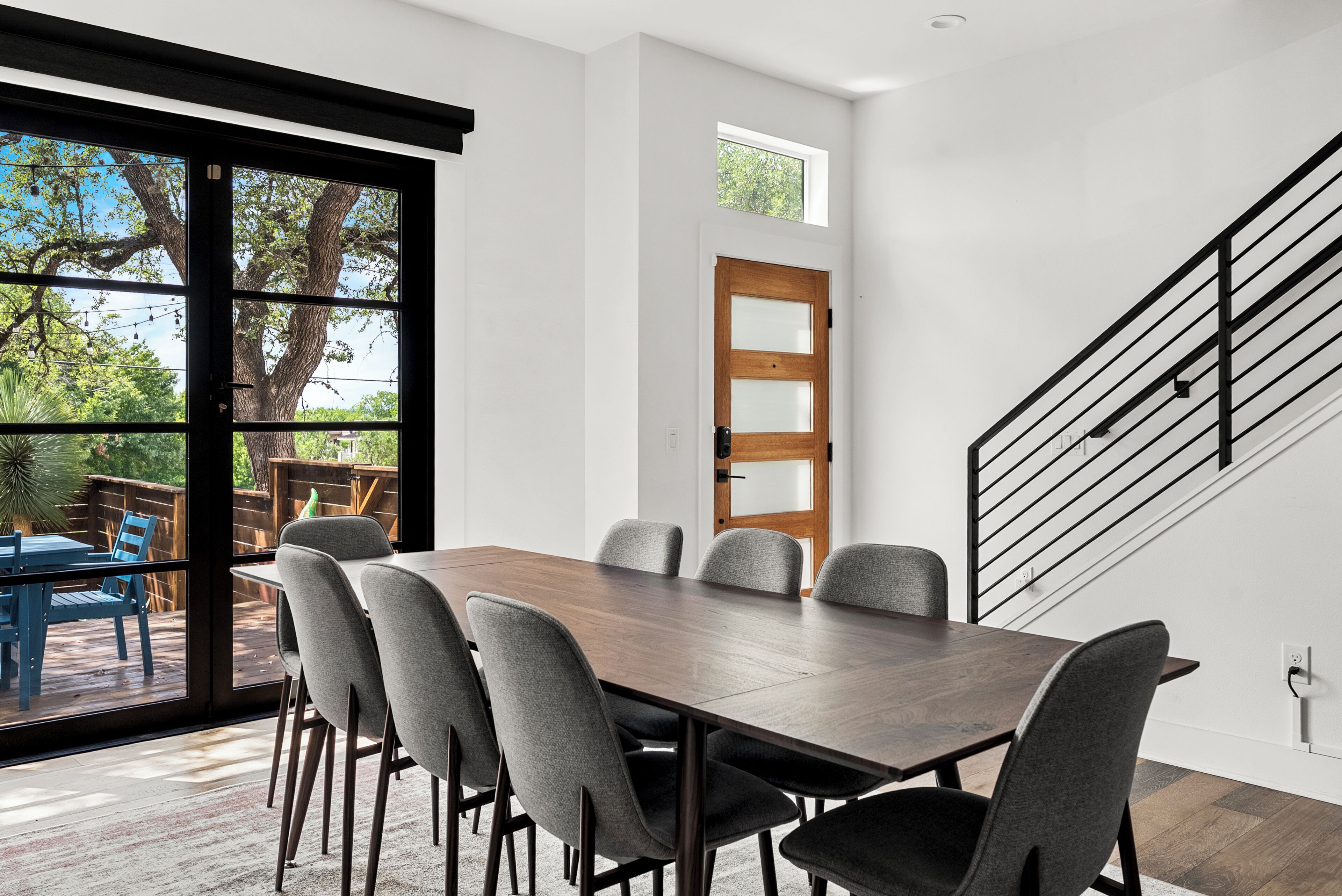 Een moderne eetruimte met een grote tafel en stoelen, een houten deur en een trap.
