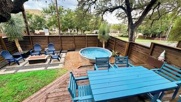 Ein Garten mit Whirlpool, Holzterrasse und Sitzgelegenheit im Freien.