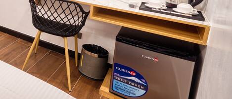 Una pequeña cocina con mostrador, lavamanos, cubo de basura y refrigerador compacto.