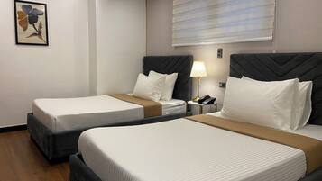A hotel room with two beds, a bedside table with a lamp, and a wall-mounted painting.