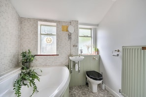 A bathroom with a bathtub, toilet, sink, and a window with a view.