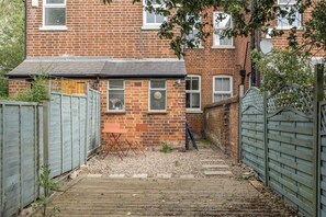 A brick house with a wooden deck, a gate, and a small garden area. - Victorian Terrace near Uni, sleeps 6, Garden (Reading)