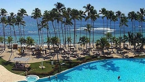 Une piscine bordée de palmiers, avec vue sur la plage.