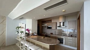 Une cuisine moderne dotée d’un îlot central, de tabourets de bar et d’appareils électroménagers intégrés.