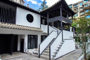 Ein traditionelles Gebäude mit einer Treppe, einem überdachten Balkon und einem kleinen Garten.