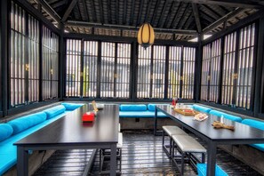 A room with a long table, blue cushioned seating, and large windows with vertical blinds. - Gongxili - Xijian Hotel (Kunming)