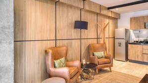 Een moderne woonkamer met twee leren fauteuils, een klein rond tafeltje en een bank.