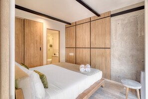 Ein modernes Schlafzimmer mit einem großen Bett, einem Holzschrank und einem kleinen runden Tisch.