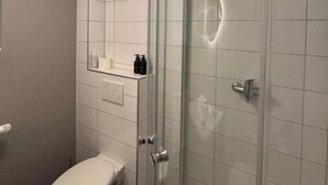 Une salle de bain moderne équipée de toilettes, d’une douche à parois de verre et d’un miroir.