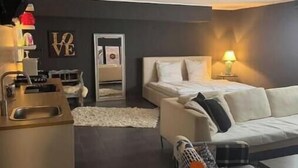 Un salon moderne avec un canapé, un coin repas comprenant une table et des chaises, et un espace cuisine avec un évier et un plan de travail.