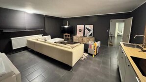 Un salon moderne avec un canapé, un téléviseur et des œuvres d’art accrochées au mur.