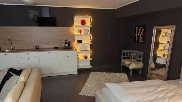 Une chambre moderne avec un lit, un canapé, un petit bureau et une table de chevet.