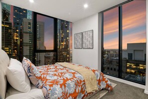 Een slaapkamer met een groot bed, stadszicht en een raam.