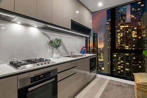 Een moderne keuken met een gasfornuis, oven en een groot raam met uitzicht op de stad.