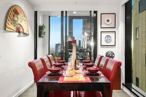 A dining area with a city view, a decorative fan, and framed artwork. - Modern City Gem 3BR | Pool, Gym and 2 Free Parking (Southbank)
