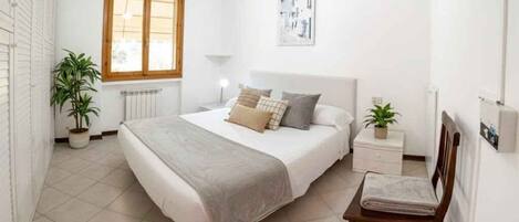 Een slaapkamer met een bed, nachtkastjes, een stoel, een raam en een radiator.
