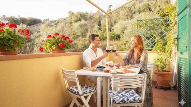 A terrace with a table and chairs, potted plants, and a view of the surrounding landscape. - Holiday apartment mit Klimaanlage und Balkon (Imperia)