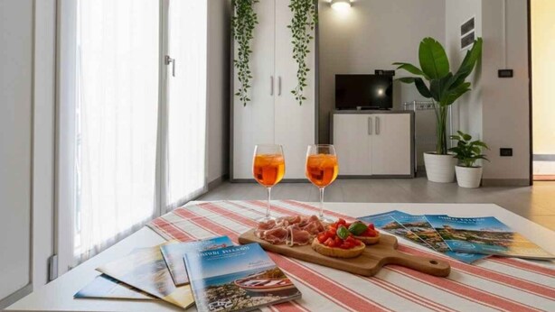 Una habitación con una mesa de comedor dispuesta con comida, dos vasos de bebida y folletos turísticos.