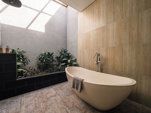 Un baño moderno con una bañera independiente, un cabezal de ducha e incluso un jardín vertical integrado.