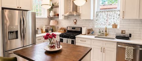 A modern kitchen with white cabinets, stainless steel appliances, a central island, and pendant lighting.
