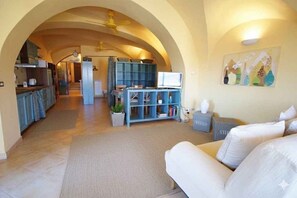 An open-plan living area with a kitchen, a sofa, a television, and a bookshelf. - Holiday apartment with balcony and internet (Imperia)