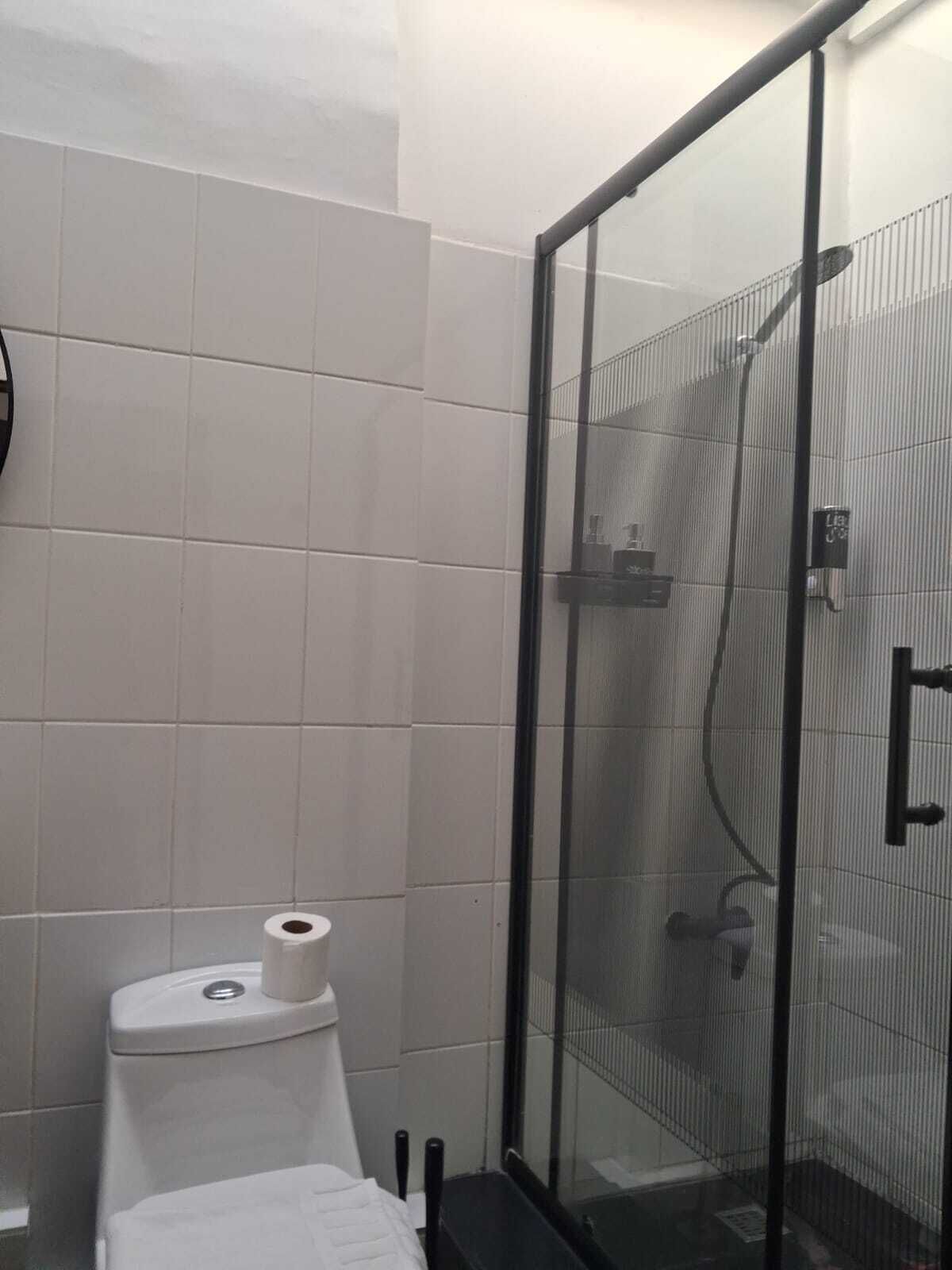 Ein Badezimmer mit einer Duschkabine, einer Toilette und einer Toilettenpapierrolle.