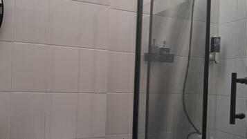 Ein Badezimmer mit einer Duschkabine, einer Toilette und einer Toilettenpapierrolle.